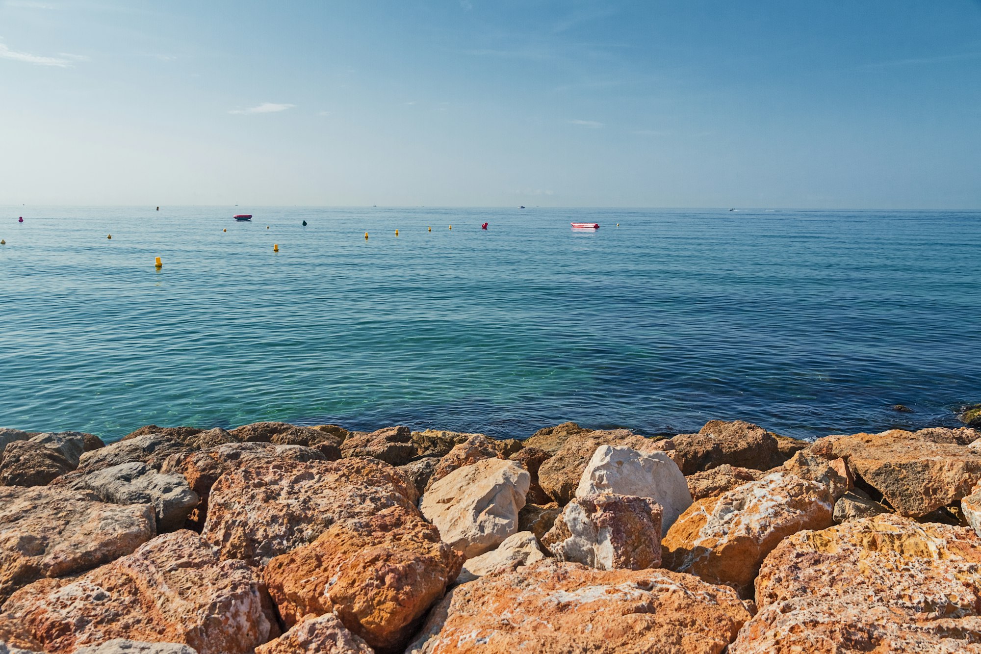 Mediterranean beach in early morning with buoys and hot stones, Salou, Catalonia, Spain